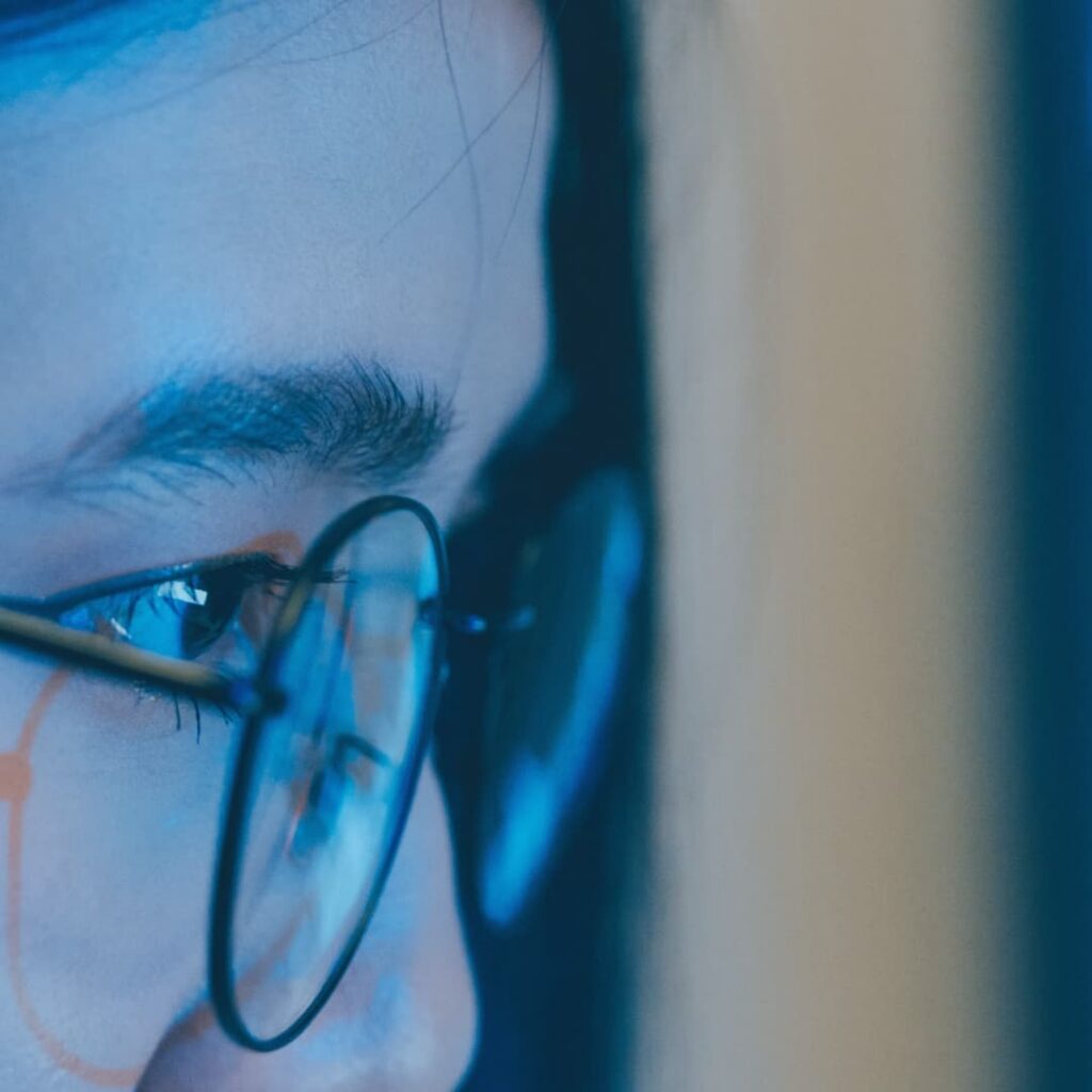 Woman looking at screen with data reflecting in glasses