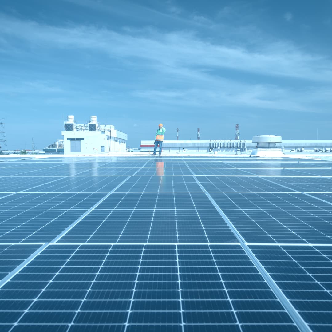 Worker in high-vis standing on top of a solar panel against a stormy sky