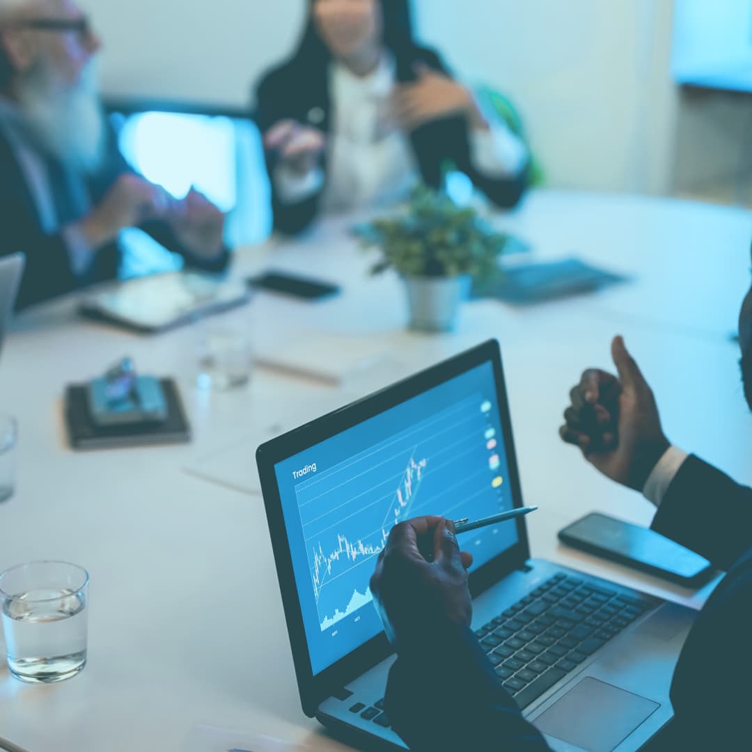Business meeting showing man working on laptop with a data graph on