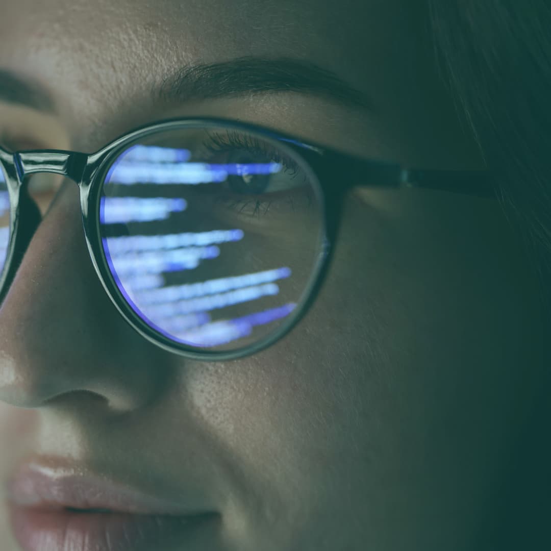 Woman looking at screen with lines of light reflecting in glasses